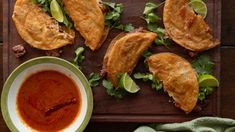 an overhead view of some food on a wooden tray with a bowl of sauce and napkins