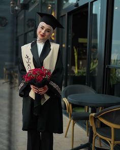 a person in a graduation gown holding flowers