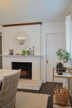 a living room with a fire place and a table in front of a mirror on the wall