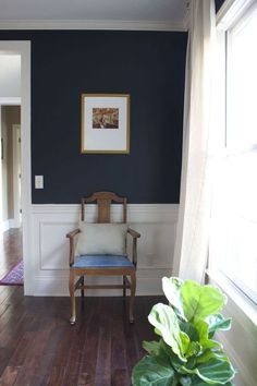 a chair sitting in the middle of a living room next to a potted plant