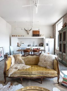 a living room filled with furniture next to a kitchen and dining room table in front of a brick wall