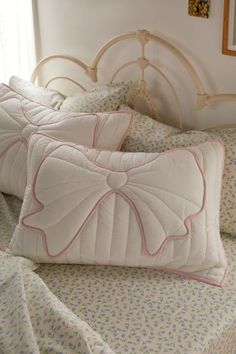 two pillows sitting on top of a bed next to each other