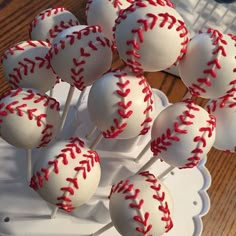 baseball cake pops with red stitching on them sitting on a white plate, ready to be eaten