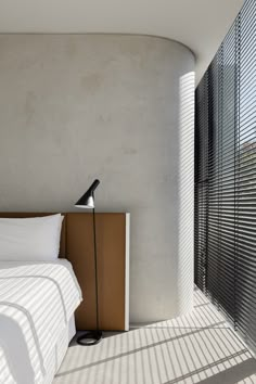 a bed sitting under a window next to a wooden cabinet and lamp on top of a table