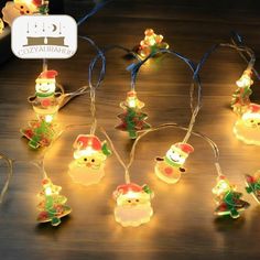 christmas lights with santa claus and snowmen on them are sitting on a wooden table