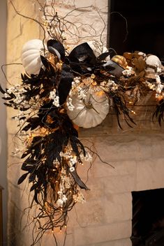 a fireplace decorated with white pumpkins and black ribbon