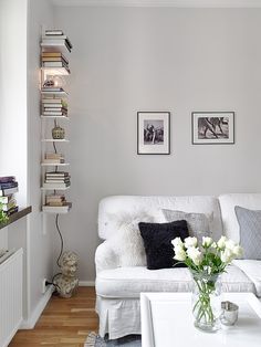 a living room with white furniture and pictures on the wall