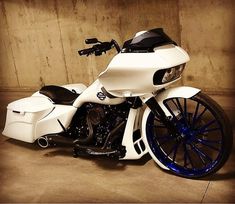 a white and black motorcycle parked in a room next to a wall with blue rims