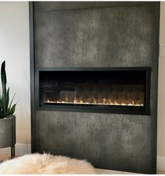 a modern fireplace in a living room with a fur rug on the floor and a potted plant next to it