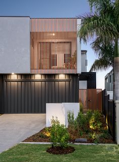 a modern house with wooden slats on the side and palm trees in the front yard