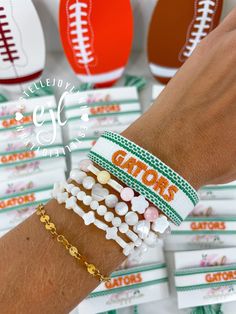 a person's arm with several bracelets and football balls on the table in front of them