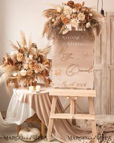 a welcome sign with flowers and feathers on it sitting next to a wooden easel