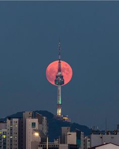 the full moon is seen rising over a city