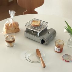 a toaster sitting on top of a white table next to a bag of bread