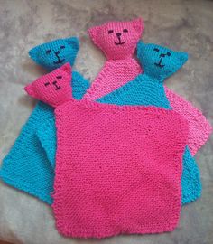 three knitted teddy bears sitting next to each other on top of a bed covered in pink and blue blankets