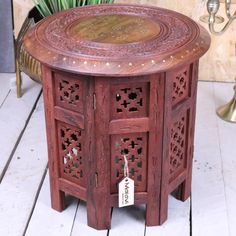 an ornate wooden table with a price tag attached to it's side and a potted plant in the background