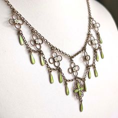 This antique silver and green and white enamel necklace was hand crated in the Arts and Crafts era, around 1910 by famed Norwegian silver smith Marius Hammer. Hammer lived from 1847-1927 and worked in Bergen, Norway. This drop necklace features flowers and drops of bright spring green and matte what enamel with that velvety look that Hammer was a master of. Chains of silver weave throughout this necklace, piecing together a lovely statement piece of swirls, loops, and twists. This piece weighs 10.3 grams and measures 16 inches in length. It has been acid tested. A mark on the back reads, ‘930S’, indicating fine silver and it bears the hallmark of the M with a hammer forming the center.  Wearable on a Saturday night date, give-able for a wedding present, presentable at a cocktail party, and Whimsigoth Necklace, Fae Necklace, Antique Silver Jewelry Necklace, Art Nouveau Jewelry Vintage, Fairycore Necklace, Norwegian Jewelry, Arts And Crafts Era, Medieval Necklace, Festoon Necklace