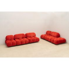 two red couches sitting next to each other on a white floor in front of a wall