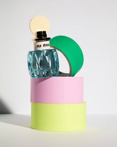 a bottle with a green cap on top of a pink and yellow container