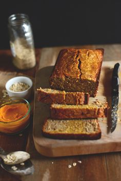 sliced loaf of bread sitting on top of a cutting board next to two small bowls