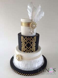 a three tiered black and white wedding cake with feathers on it's side