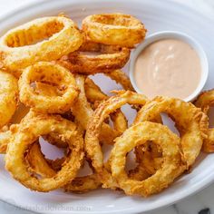 onion rings with dipping sauce on a white plate