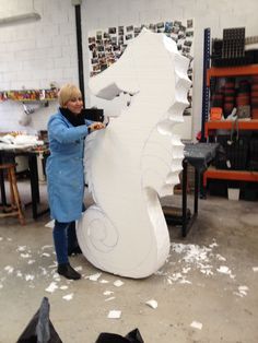 a woman standing next to a large white sculpture