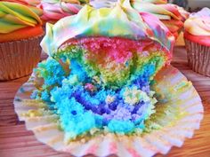 cupcakes with different colored frosting sitting on top of a wooden table next to each other