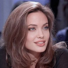 a close up of a woman with long hair and blue eyes looking at the camera