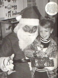 an old black and white photo of santa claus giving a boy something to give him