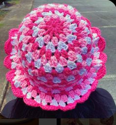 a pink and white crocheted hat sitting on top of a table