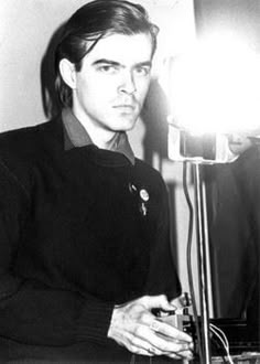 a black and white photo of a young man in front of a camera with a light on it