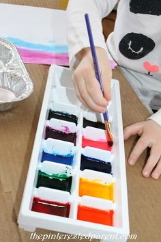 a child is painting with watercolors in a box