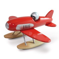 a red toy airplane is sitting on a wooden stand