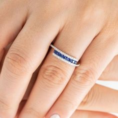 a woman's hand with a blue and white diamond ring on her left hand