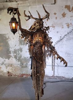 a sculpture made out of branches and chains with a light hanging from it's side