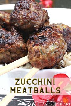 some meatballs with chopsticks are on a plate and the words zucchini meatballs above it