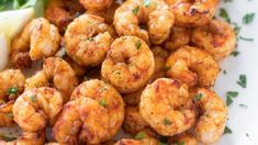 some shrimp is on a white plate and garnished with parsley next to lemon wedges