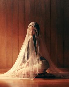 a woman sitting on the floor with a veil over her head