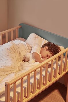 a small child sleeping in a wooden bed