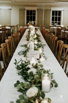 a long table with candles and greenery on it is set up for an event