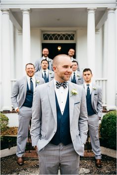 a group of men standing next to each other in front of a white building with columns