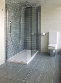 a bathroom with a toilet, shower and tiled flooring in it's walls