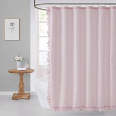 a pink shower curtain with ruffles on the edge in a white bath room