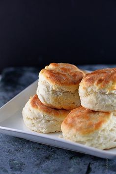 four biscuits on a white plate sitting on a table