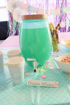 a table topped with cups and bowls filled with food next to a green drink pitcher