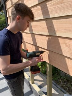 a man is using a drill to attach siding