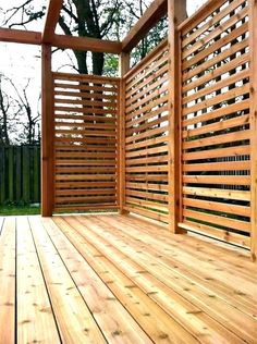 a wooden deck with trellis on the side and trees in the backgroud