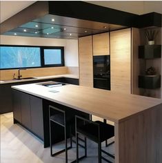 a modern kitchen with an island counter and bar stools in front of the window