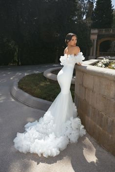 a woman in a white wedding dress leaning against a wall